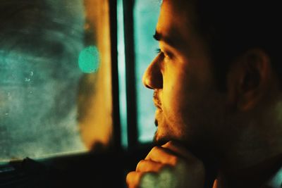 Close-up of thoughtful young man looking through window