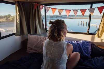 High angle view of woman lying on bed by window