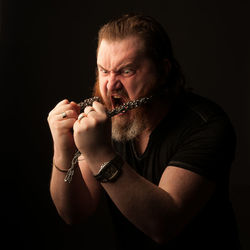 Portrait of man smoking cigarette against black background