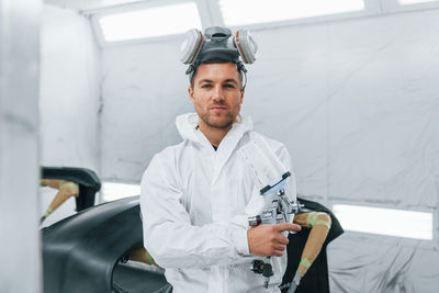 Painting the car. man in uniform is working in the auto service.