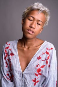 Close-up portrait of young woman against gray background