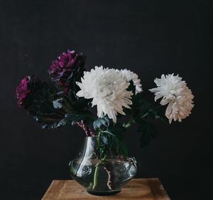 Close-up of flower vase on table against black background