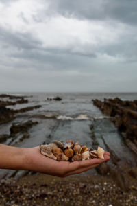 Pebbles on rocks at beach against sky