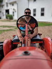 Portrait of father and son sitting on tractor 