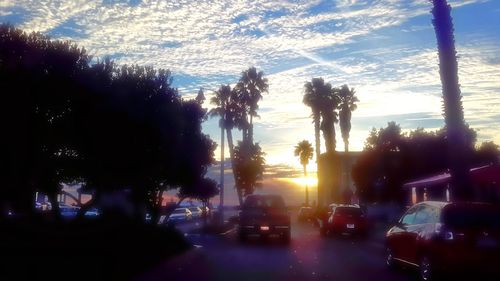 Cars on road against cloudy sky