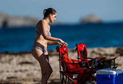 Full length of shirtless woman standing on beach