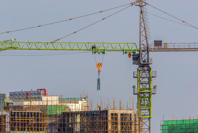 Low angle view of cranes at construction site against sky