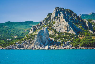 Scenic view of sea and mountains against clear blue sky