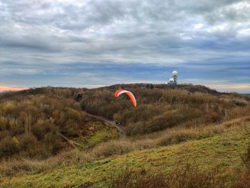 Full length of person paragliding on field against sky