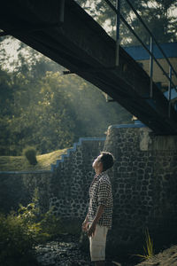 Rear view of the man standing under the bridge