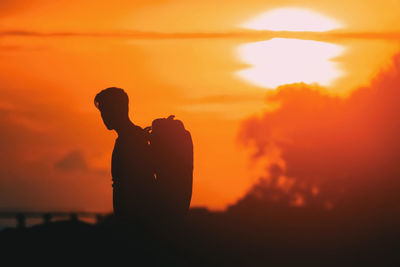 Silhouette man standing against orange sky