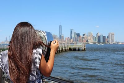 Rear view of woman using binoculars against sky