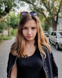 Portrait of young woman wearing leather jacket while standing on road