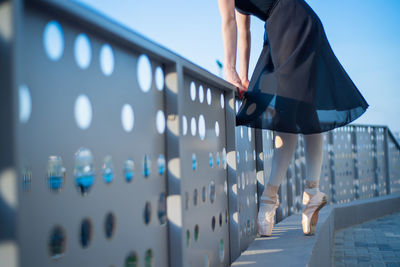 Low section of woman walking on railing in city