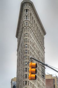 Low angle view of road signal in front of flat iron building