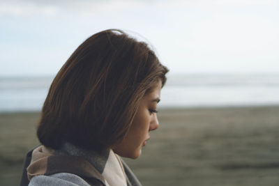 Side view of young woman with sea in background