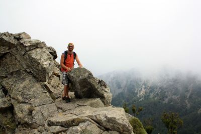 Portrait man standing on rock against mountain against sky 