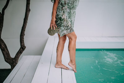 Low section of woman standing by swimming pool