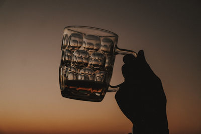 Close-up of hand holding beer against yellow background