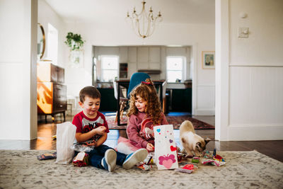 Young brother and sister sitting on floor opening valentines