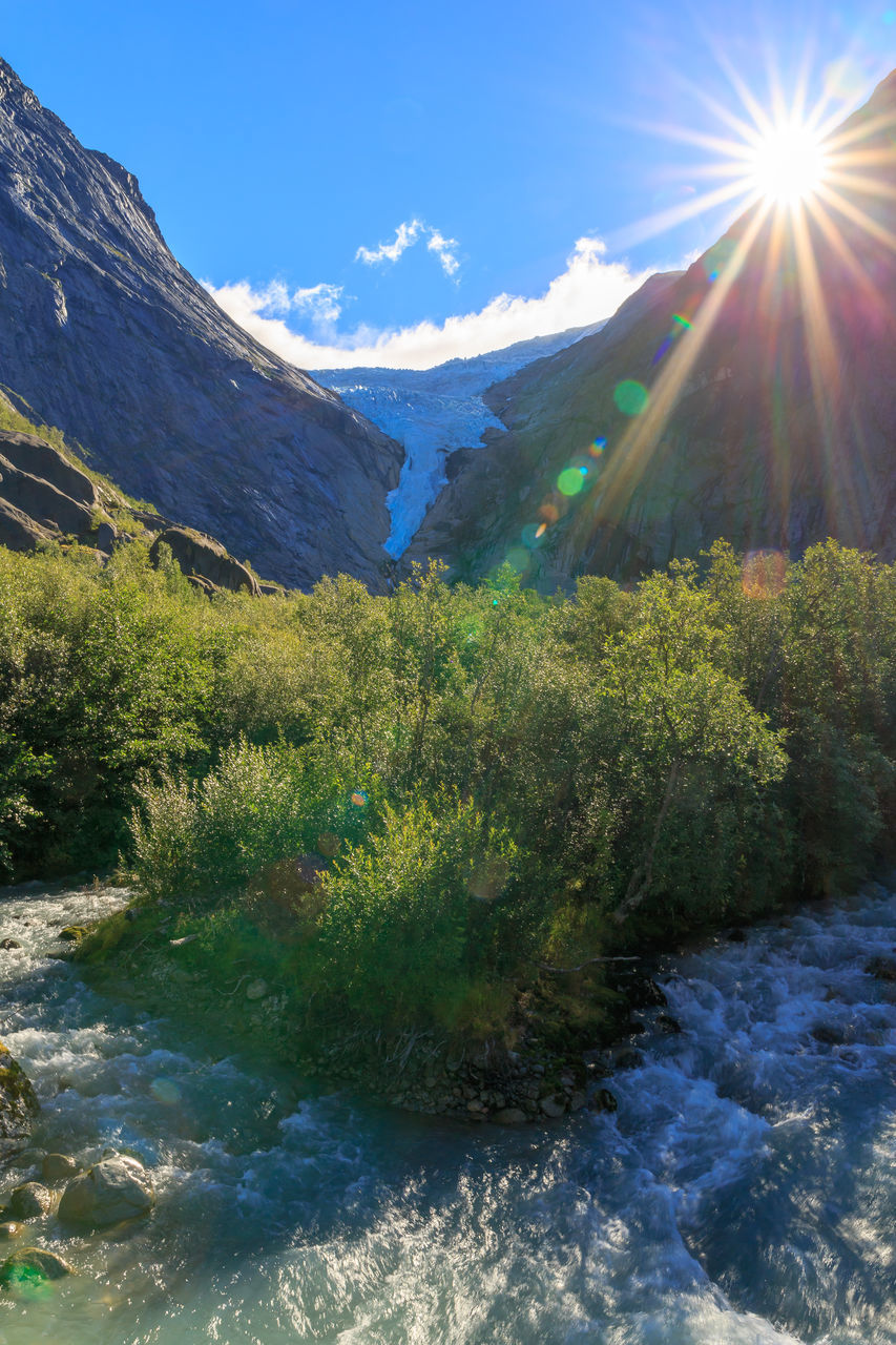 mountain, scenics - nature, environment, beauty in nature, sky, nature, landscape, sunlight, mountain range, land, water, plant, lens flare, valley, wilderness, sun, snow, sunbeam, lake, tree, sunny, no people, tranquility, blue, travel, forest, travel destinations, cold temperature, tranquil scene, mountain peak, outdoors, non-urban scene, winter, summer, day, coniferous tree, pine tree, idyllic, pinaceae, cloud, tourism, rock, snowcapped mountain, green, pine woodland, clear sky, environmental conservation, bright