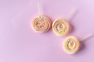 Pink round sweet meringues lie on a pink background