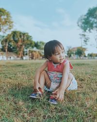 Side view of boy sitting on field