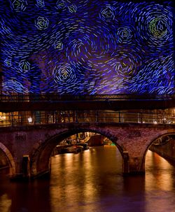 Arch bridge over river at night