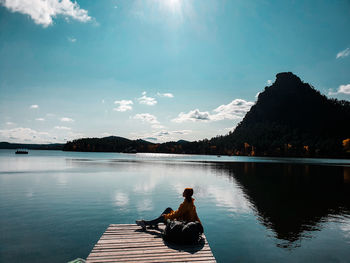 Man sitting on lake against sky