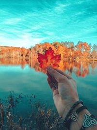 Man holding autumn leaf in lake