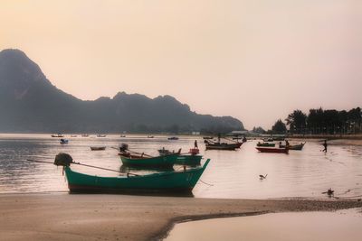 Boats moored in sea against sky during sunset