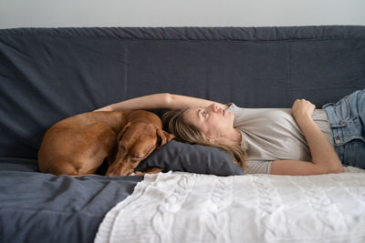 Woman with dog sleeping on sofa