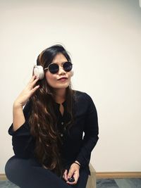 Woman sitting against white wall