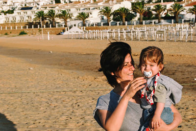 Mother carrying son while standing at beach