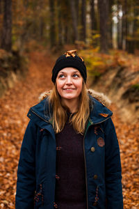 Portrait of young woman standing in forest during winter