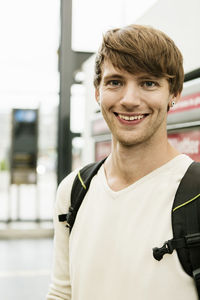 Portrait of smiling young man standing at railroad station
