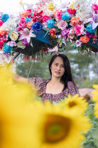 Portrait of young woman standing by flowers