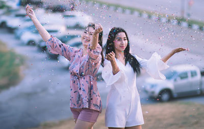 Playful young women throwing confetti in park