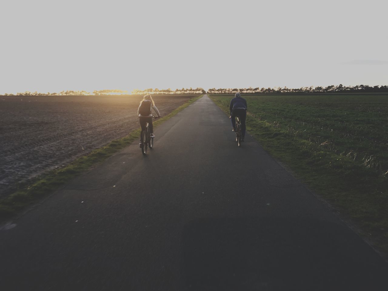 REAR VIEW OF PEOPLE RIDING MOTORCYCLE ON ROAD