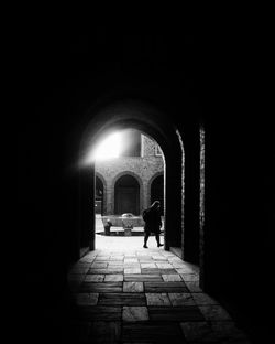 Silhouette man walking in illuminated tunnel