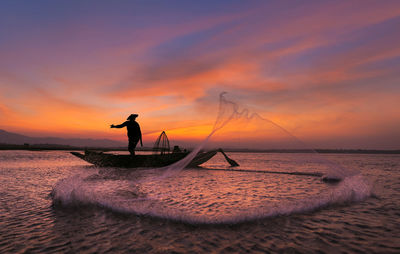 Asian fisherman with his wooden boat in nature river at the early morning before sunrise