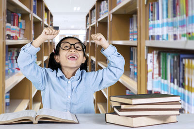 Smiling girl with books in library