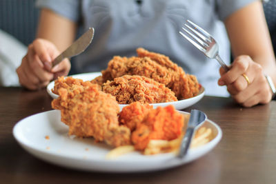 Midsection of person preparing food in plate on table