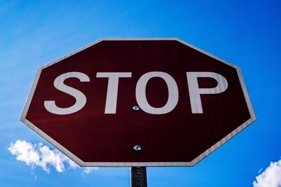 Low angle view of stop sign against blue sky