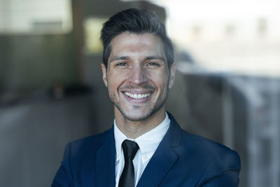 Confident businessman smiling while standing in office