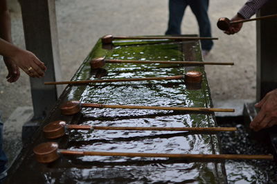 Cropped hands of people holding wooden ladle at temple