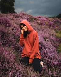 Woman kneeling on pink flowering plants on field