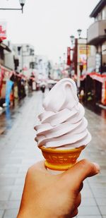 Cropped hand holding ice cream on street in city