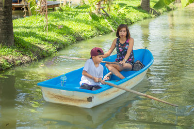 Mother and son rowing boat in water