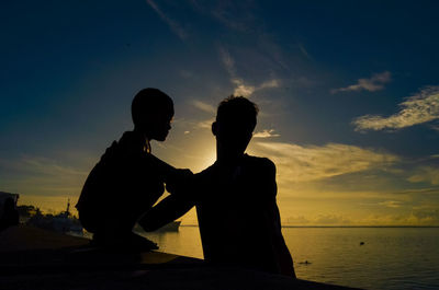 Silhouette people against sea during sunset